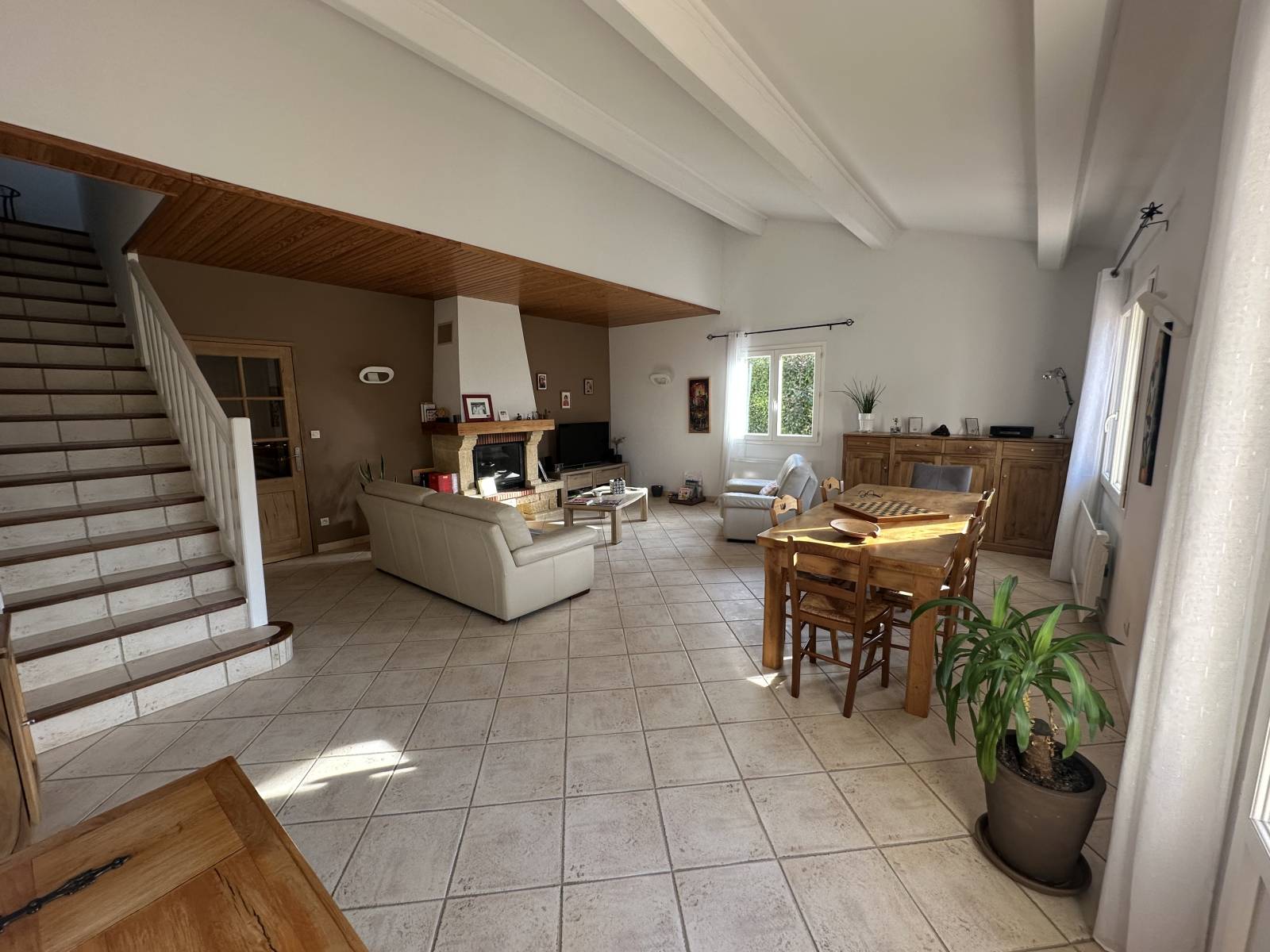 le séjour avec les poutres apparentes et la cheminée